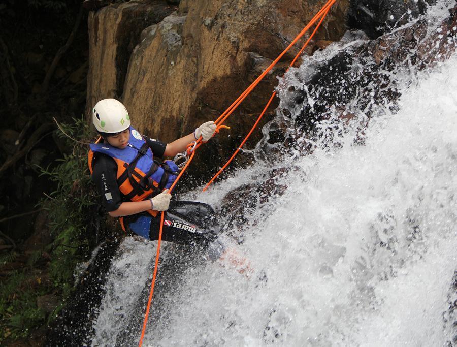 Student canyoning down a waterfall during an Inspired Education Group international holiday camp