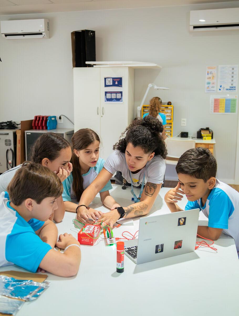 Students and a teacher building a robotics project at Escola Eleva Brasília, Asa Sul